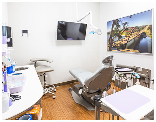 A dentist's office with a chair and a monitor.