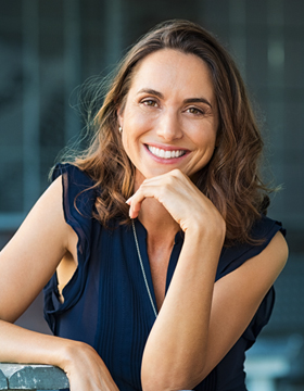 A woman in a blue top leaning against a railing.