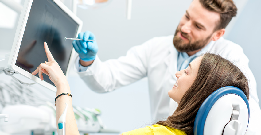 Dentist showing his patient Dental Results in a monitor