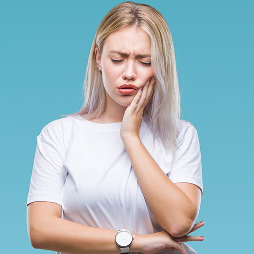 Blonde Woman suffering from a tooth ache - root Canal symptoms