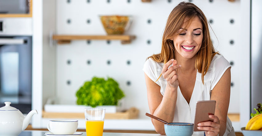 Woman is smiling with her phone on her dining table