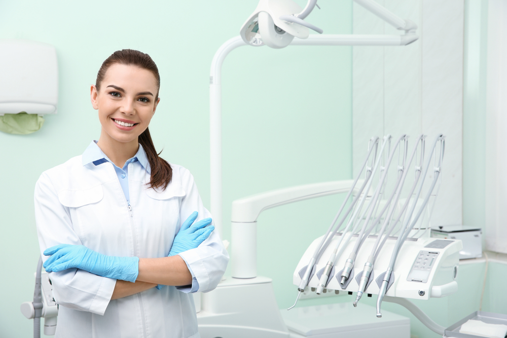 Everything You Need to Know about a female dentist standing in front of a dental machine.